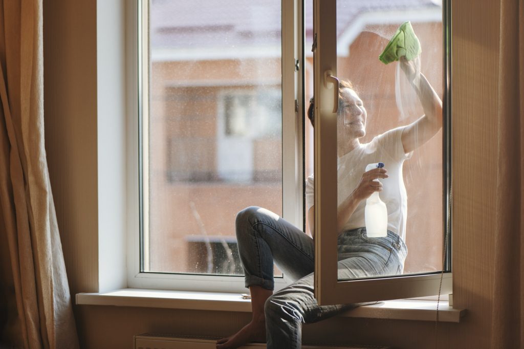 Smiling woman cleaning the window