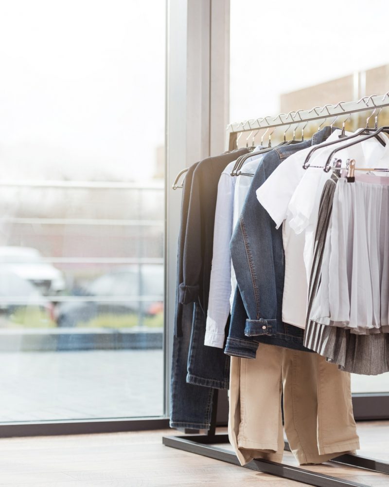 Various clothes on hager at shop interior against window